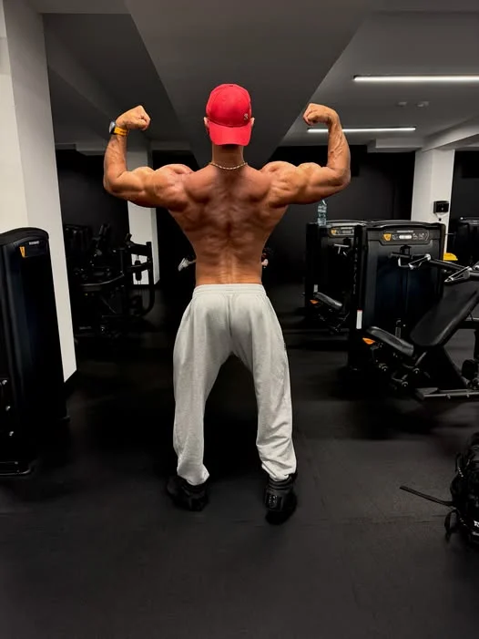 Celestyn na siłowni — poza podwójny biceps tyłem